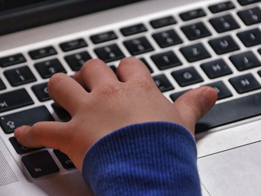 mano de niño sobre teclado de computador.